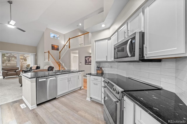 kitchen with a sink, open floor plan, light wood-type flooring, ceiling fan, and appliances with stainless steel finishes