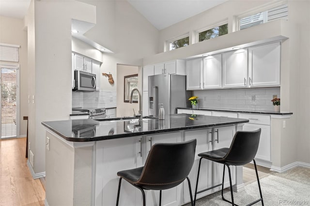 kitchen with a sink, a kitchen bar, decorative backsplash, plenty of natural light, and appliances with stainless steel finishes