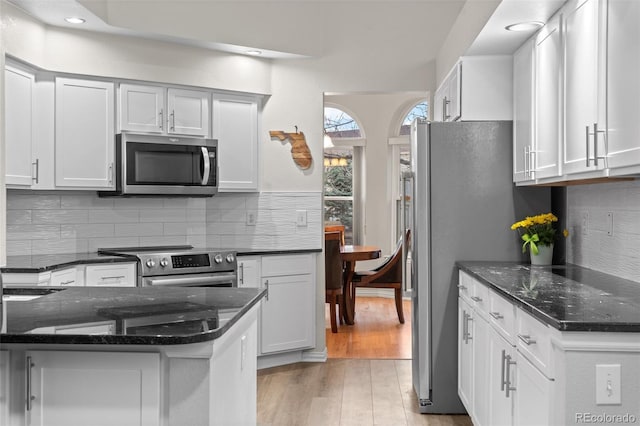 kitchen with stainless steel appliances, white cabinetry, light wood-type flooring, decorative backsplash, and recessed lighting