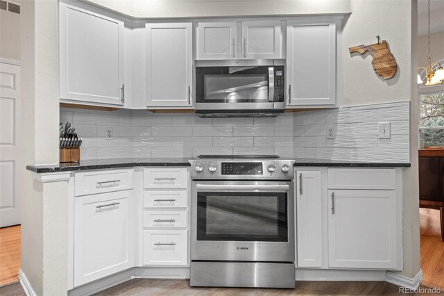 kitchen featuring dark stone counters, appliances with stainless steel finishes, tasteful backsplash, and light wood-style floors