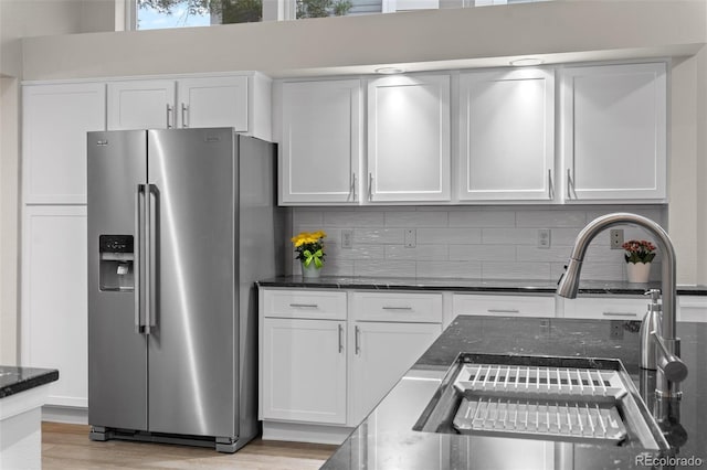 kitchen featuring a sink, white cabinetry, decorative backsplash, and stainless steel refrigerator with ice dispenser