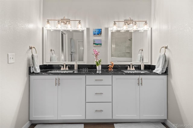 full bath with a sink, double vanity, and baseboards