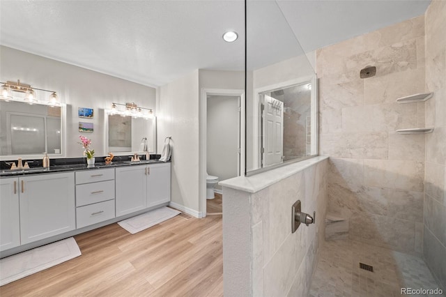 bathroom with walk in shower, double vanity, toilet, and wood finished floors
