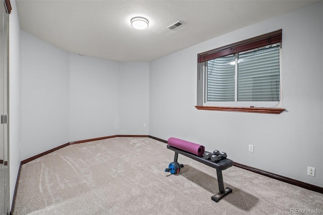 workout room with a textured ceiling, carpet, baseboards, and visible vents