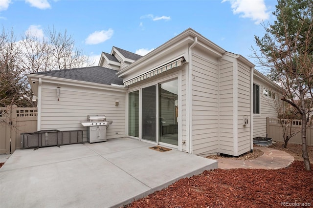 rear view of house with a patio area, a shingled roof, and fence