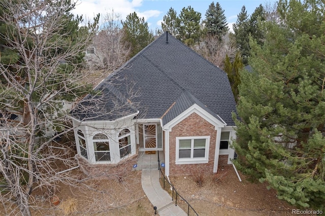 exterior space with brick siding and roof with shingles