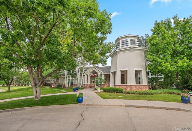 view of front of house with a front lawn, stucco siding, and brick siding
