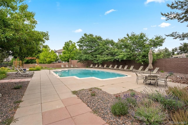 community pool with a patio and a fenced backyard