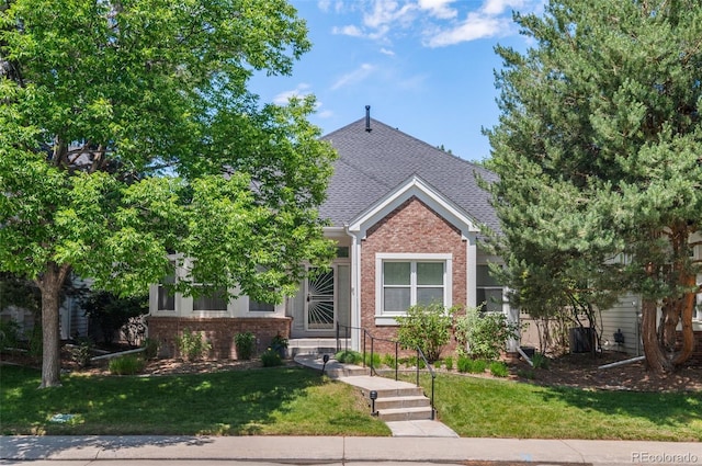 1011 S Valentia St Unit 3, Denver, CO 80247 - obstructed view of property with brick siding, a front yard, and a shingled roof