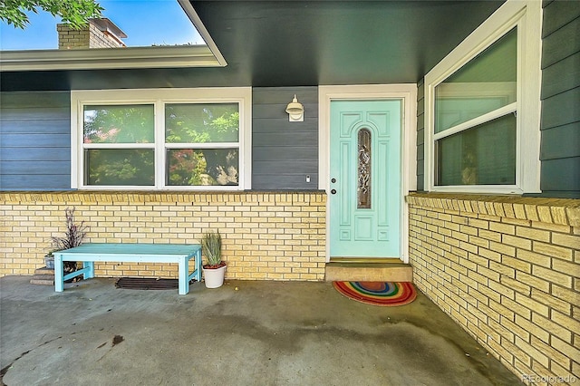 property entrance with brick siding and a patio