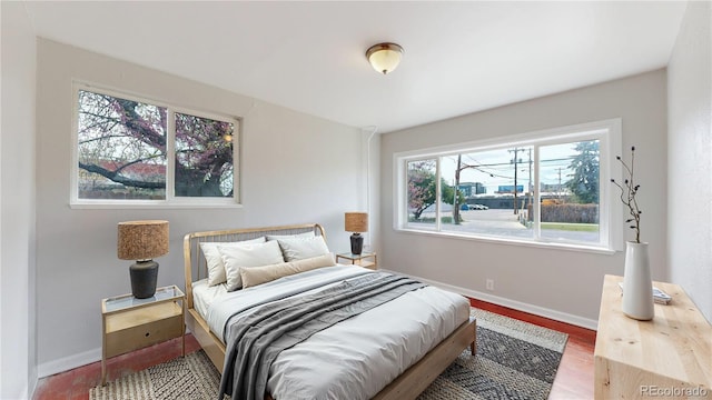 bedroom with baseboards, multiple windows, and wood finished floors