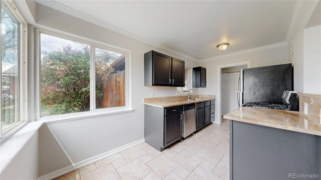 kitchen with stone finish floor, baseboards, ornamental molding, a sink, and stainless steel appliances