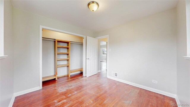 unfurnished bedroom featuring baseboards, a closet, light wood-style flooring, and visible vents