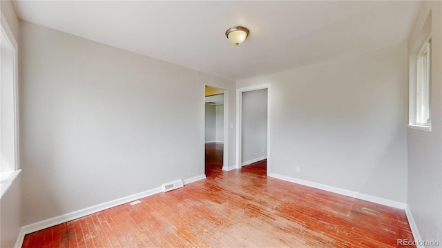 empty room featuring visible vents, light wood-style flooring, and baseboards