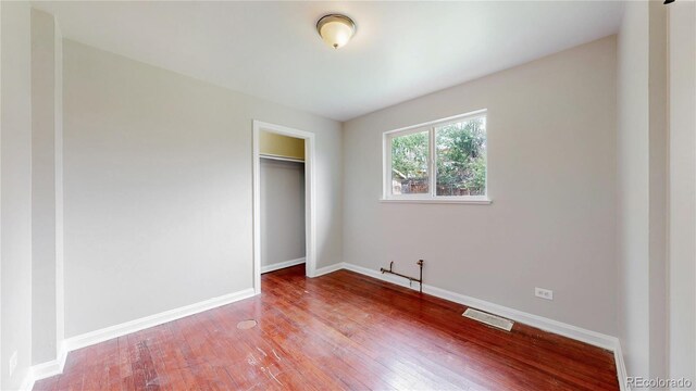 unfurnished bedroom featuring a closet, visible vents, wood finished floors, and baseboards