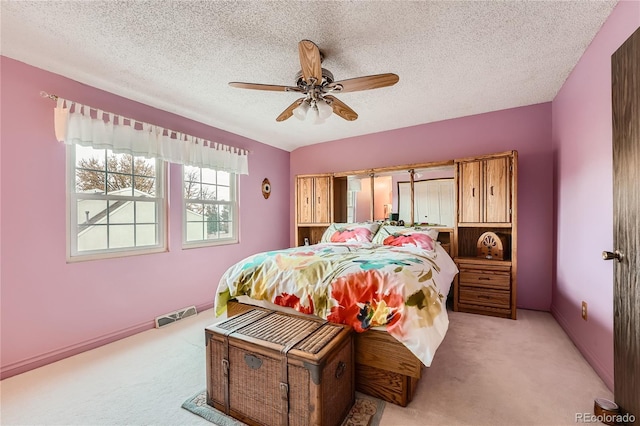 bedroom featuring light carpet, a textured ceiling, and ceiling fan