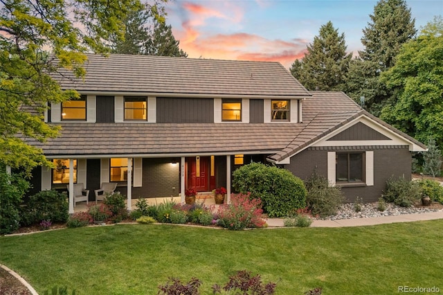 6128 S Coventry Ln E, Littleton, CO 80123 - view of front facade with brick siding, a front yard, covered porch, and a tiled roof