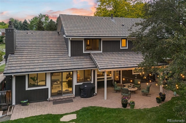 6128 S Coventry Ln E, Littleton, CO 80123 - back of house at dusk featuring a chimney, a patio area, and a lawn