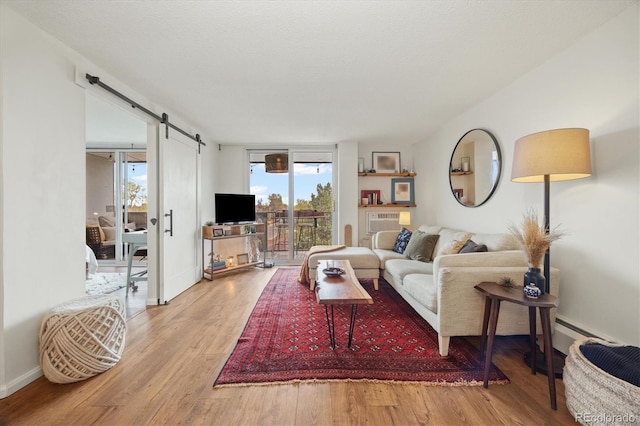 living area with baseboards, a barn door, and wood finished floors