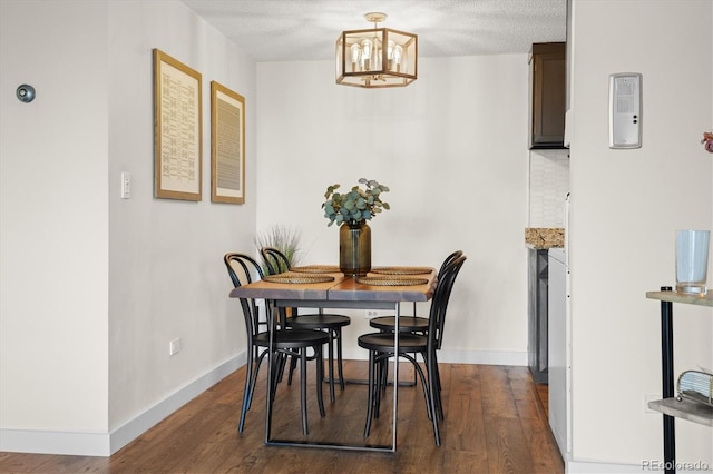 dining space with baseboards, wood finished floors, and a notable chandelier
