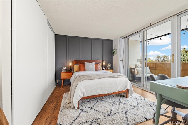 bedroom featuring expansive windows, access to exterior, and wood finished floors