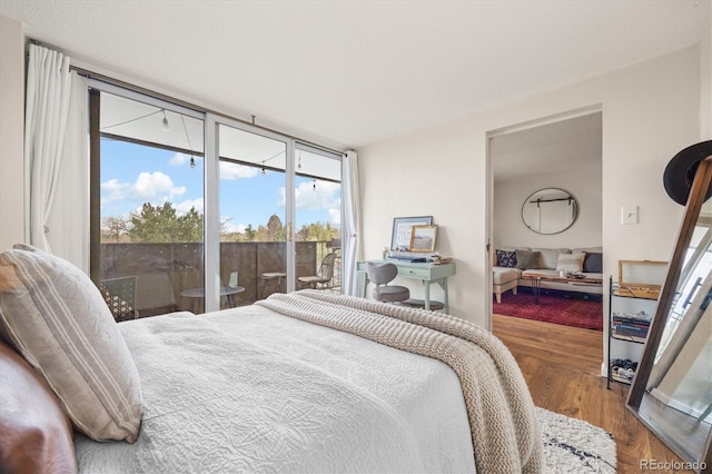 bedroom with access to exterior, wood finished floors, and multiple windows