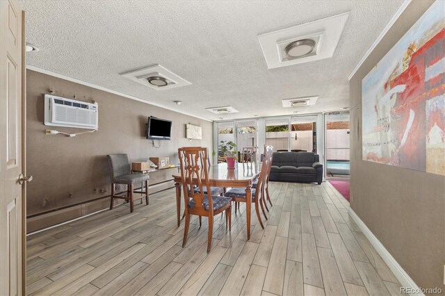 dining space featuring light wood-style floors, baseboards, an AC wall unit, and a textured ceiling