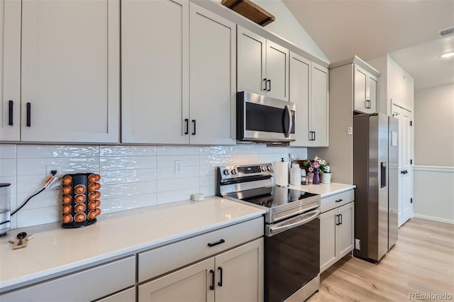 kitchen featuring stainless steel appliances, light wood finished floors, visible vents, decorative backsplash, and light countertops