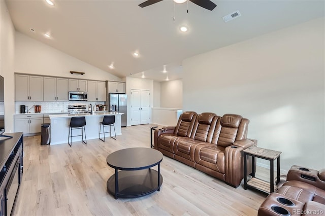 living area with high vaulted ceiling, visible vents, recessed lighting, light wood finished floors, and a ceiling fan