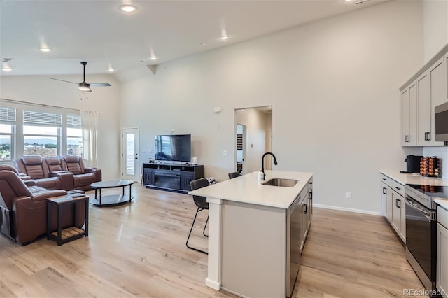 kitchen with a sink, high vaulted ceiling, a kitchen bar, open floor plan, and appliances with stainless steel finishes