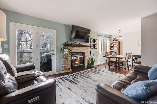 living room featuring a stone fireplace and dark hardwood / wood-style flooring