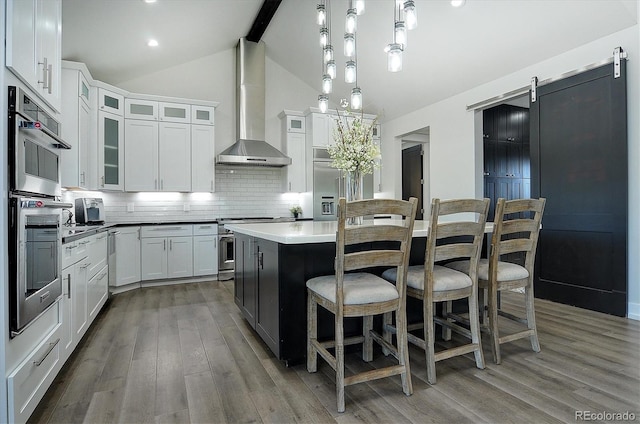 kitchen featuring pendant lighting, a center island, decorative backsplash, wall chimney range hood, and hardwood / wood-style floors