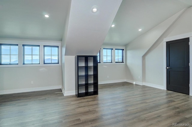 additional living space with vaulted ceiling, hardwood / wood-style flooring, and a healthy amount of sunlight