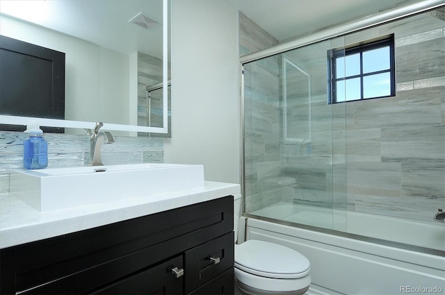 full bathroom featuring combined bath / shower with glass door, vanity, and toilet