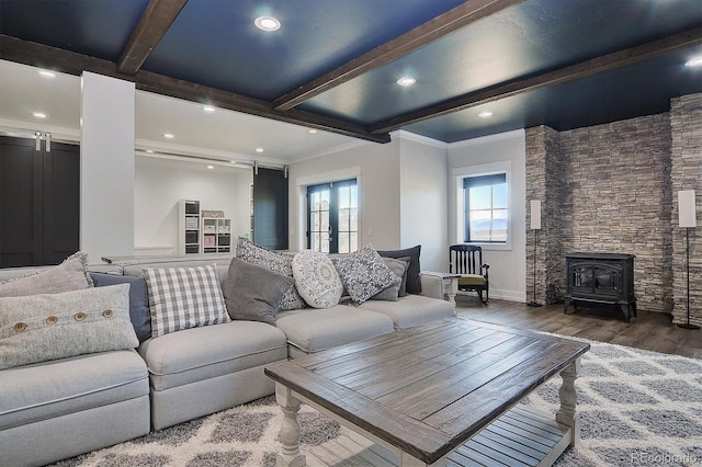 living room with a barn door, crown molding, beamed ceiling, a wood stove, and wood-type flooring