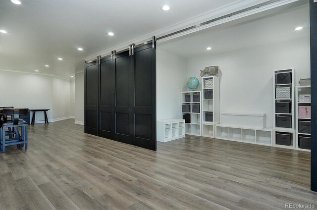 living room with light hardwood / wood-style flooring, ornamental molding, and a barn door