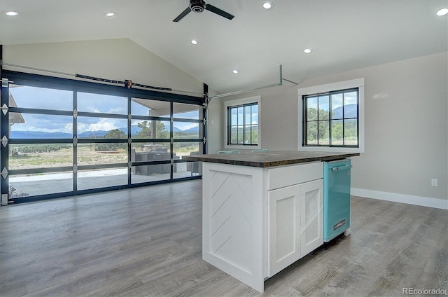 kitchen featuring ceiling fan, lofted ceiling, white cabinets, a center island, and light hardwood / wood-style floors