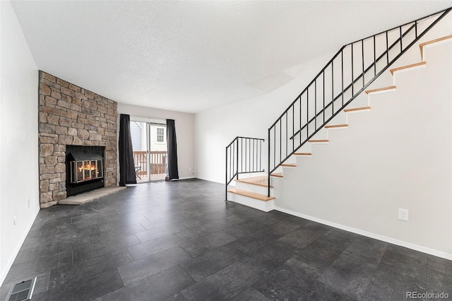 unfurnished living room with a stone fireplace and a textured ceiling