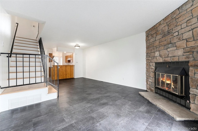 unfurnished living room with a stone fireplace and a textured ceiling