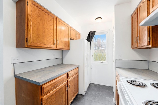 kitchen featuring white appliances, extractor fan, and dark tile patterned flooring