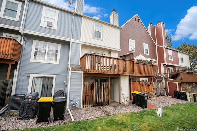 rear view of property featuring central air condition unit, cooling unit, a lawn, a wooden deck, and a balcony