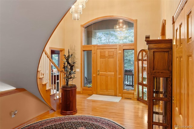 entryway with a chandelier, stairway, wood finished floors, and baseboards