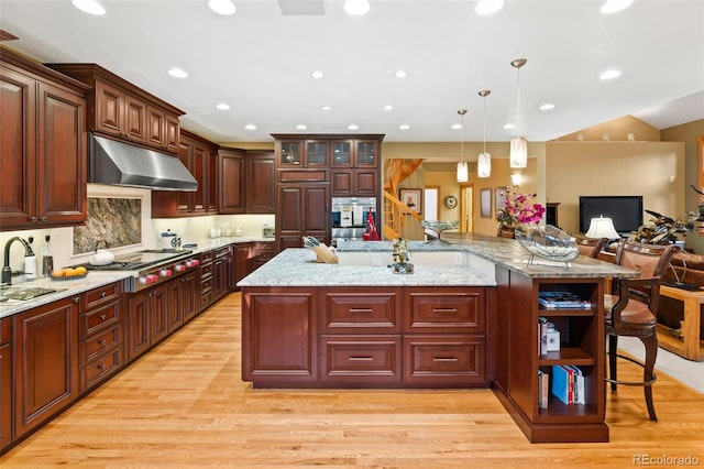 kitchen featuring stainless steel gas cooktop, light wood finished floors, and under cabinet range hood