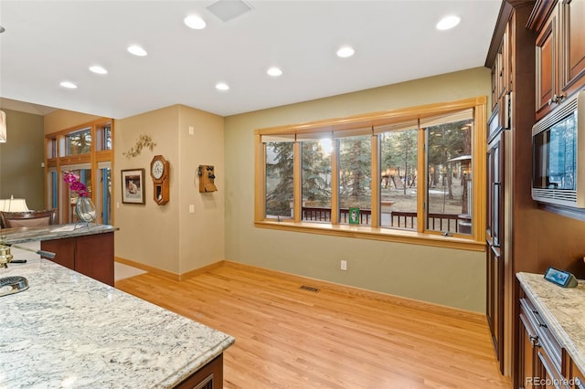 kitchen featuring light wood-style flooring, recessed lighting, light stone countertops, visible vents, and built in microwave