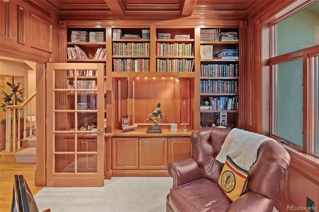 living area featuring ornamental molding, wood walls, and built in shelves