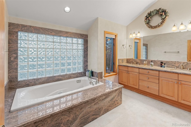 full bath featuring a garden tub, double vanity, vaulted ceiling, and a sink