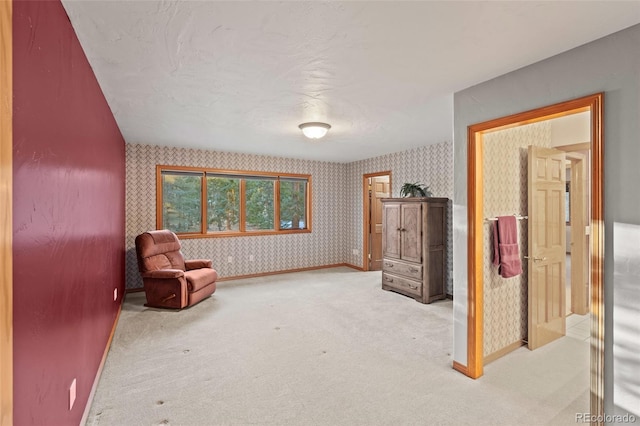 sitting room with baseboards, carpet, and wallpapered walls