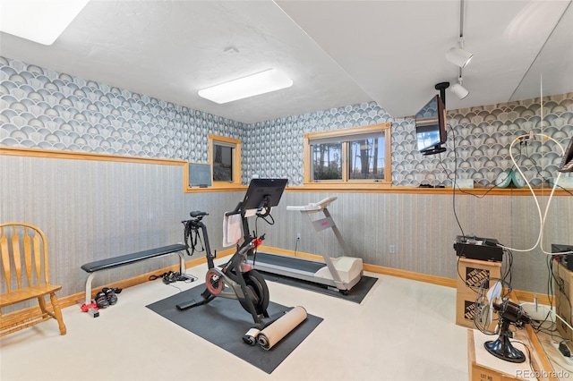 exercise area with wallpapered walls, baseboards, carpet flooring, and rail lighting