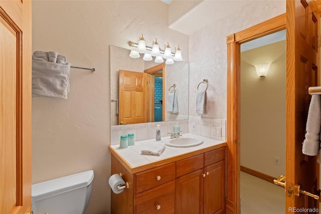 bathroom with toilet, tasteful backsplash, baseboards, and vanity