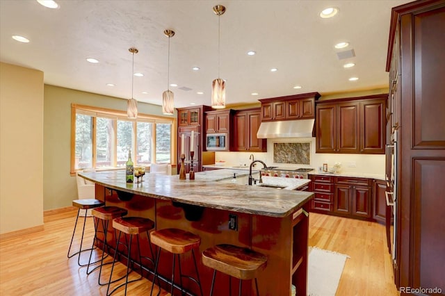 2828 Keystone Dr, Evergreen, CO 80439 - kitchen featuring under cabinet range hood, a sink, stainless steel appliances, an island with sink, and recessed lighting